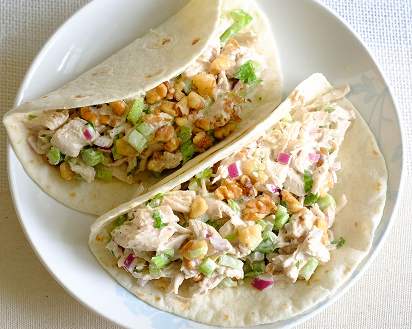 round plate with celery chicken salad wrapped in flour tortilla