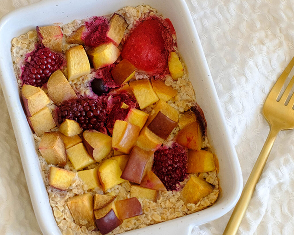 Small baking dish holding baked oats topped with apricots and mixed berries.