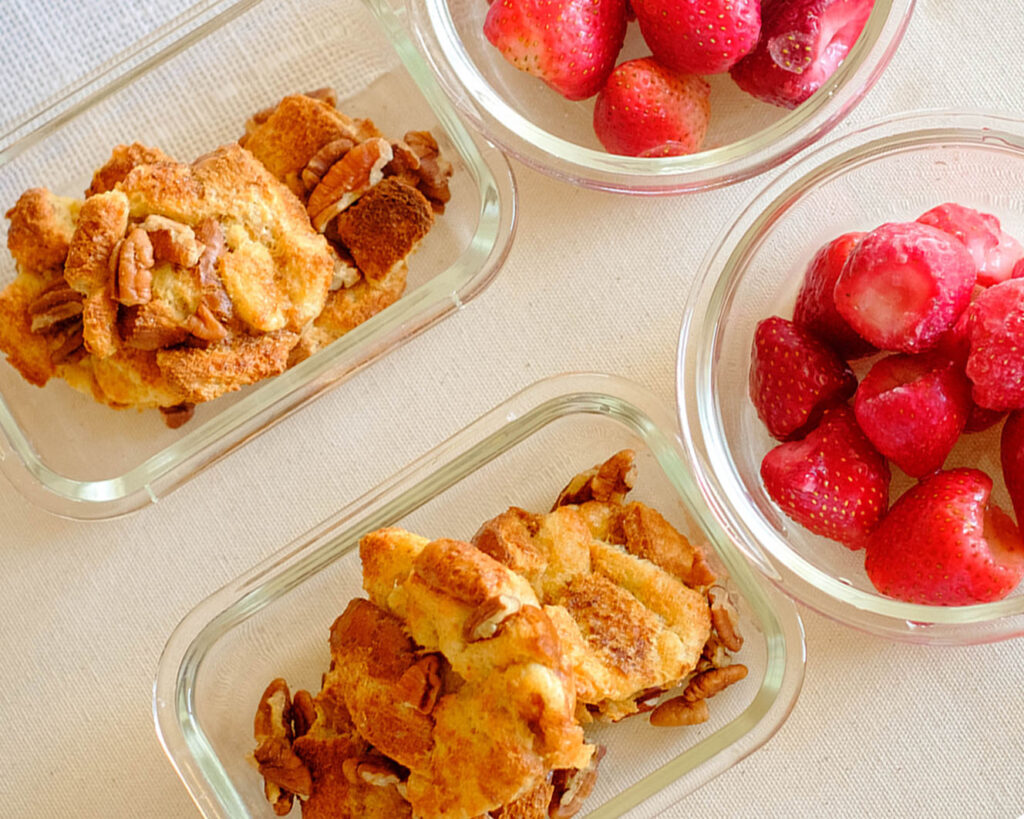 Meal prep containers storing french toast muffins and strawberries