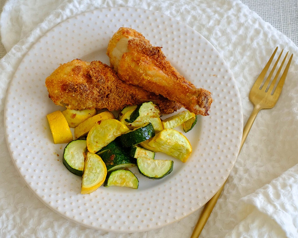 Plate with crispy Air Fryer chicken with sliced yellow squash and zucchini.