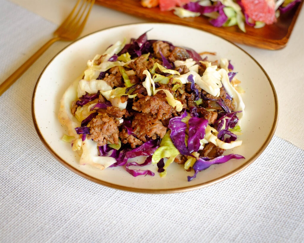 Round plate with stir fry ground beef with red and green shredded cabbage.