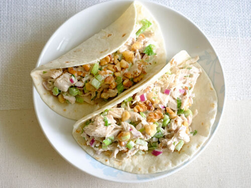 round plate with celery chicken salad wrapped in flour tortilla