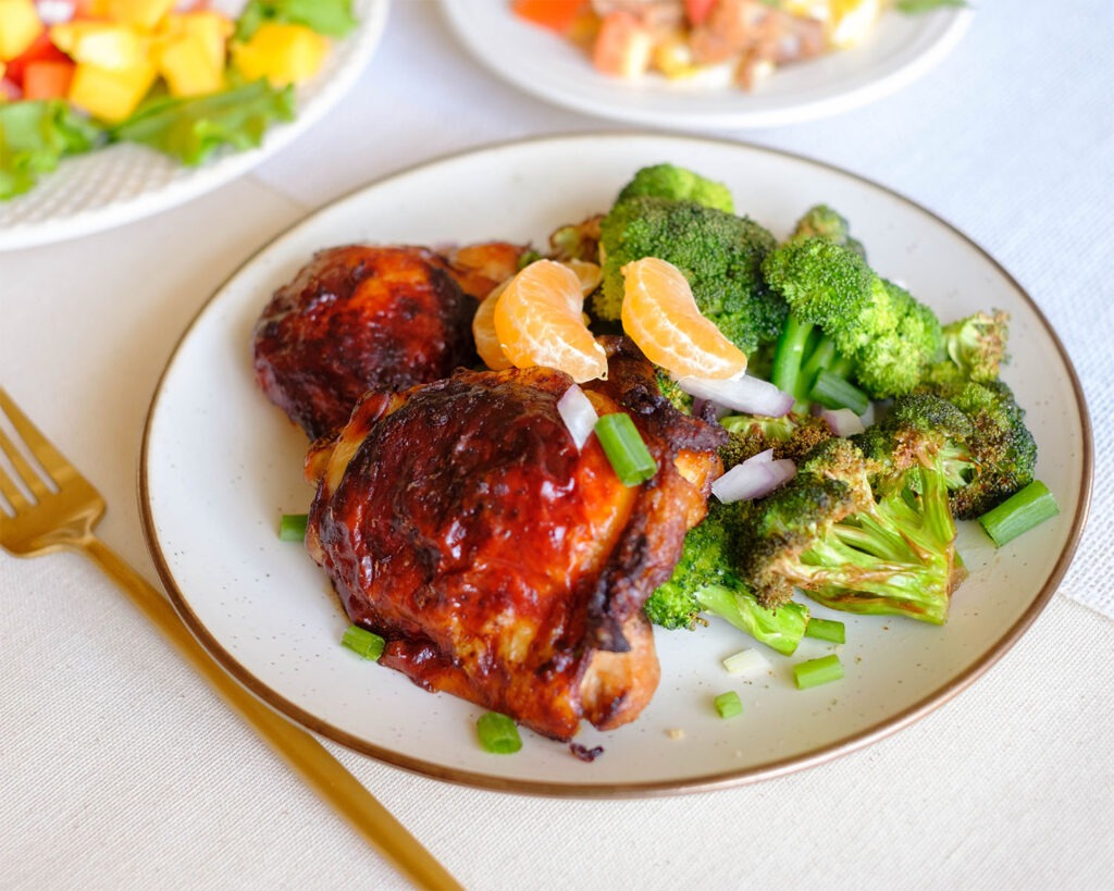 Round plate with golden brown chicken thighs and crispy broccoli florets.