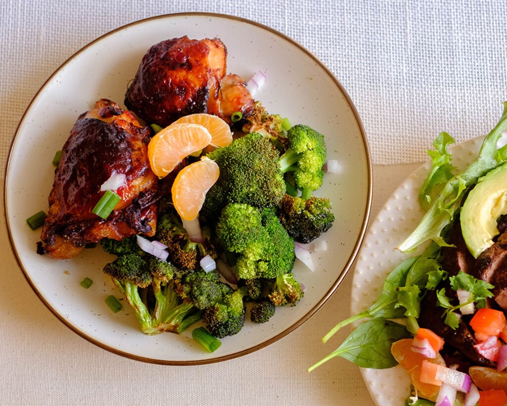Round plate with golden brown chicken thighs and crispy broccoli florets.