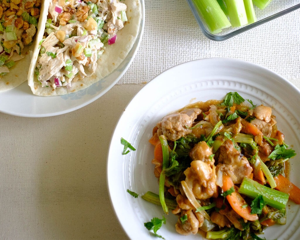 Round plate with stir fry chicken, celery, and carrots in a peanut sauce.