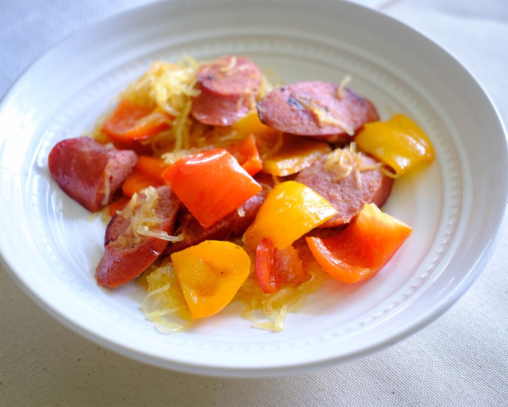 Round bowl with spaghetti squash, sausage, and bell peppers.