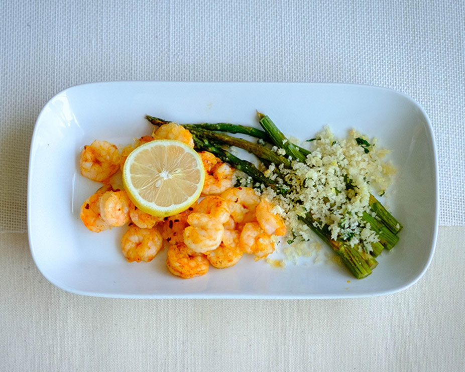Plate with baked shrimp recipe with asparagus topped with panko breadcrumbs and lemon slice.