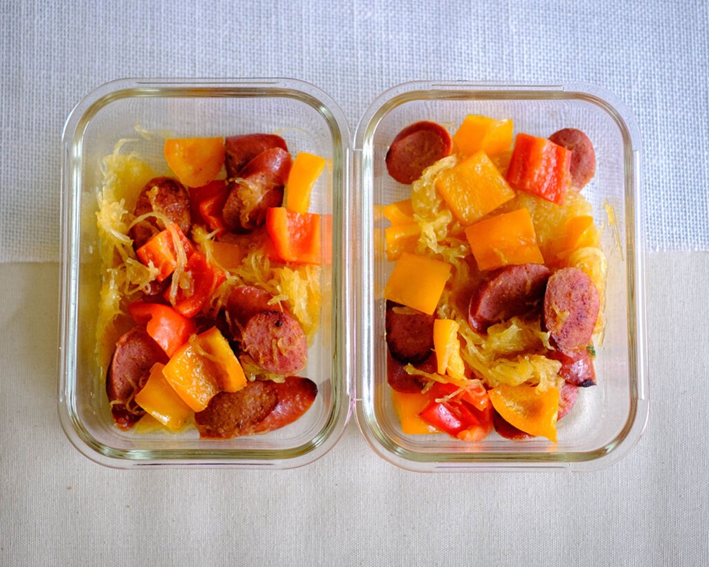 Glass meal prep containers with spaghetti squash, sausage, and bell peppers.