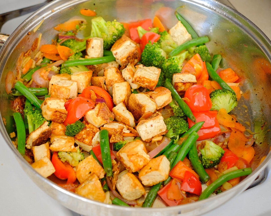 Saute pan with tofu stir fry with broccoli, red bell peppers, and cashew nuts.