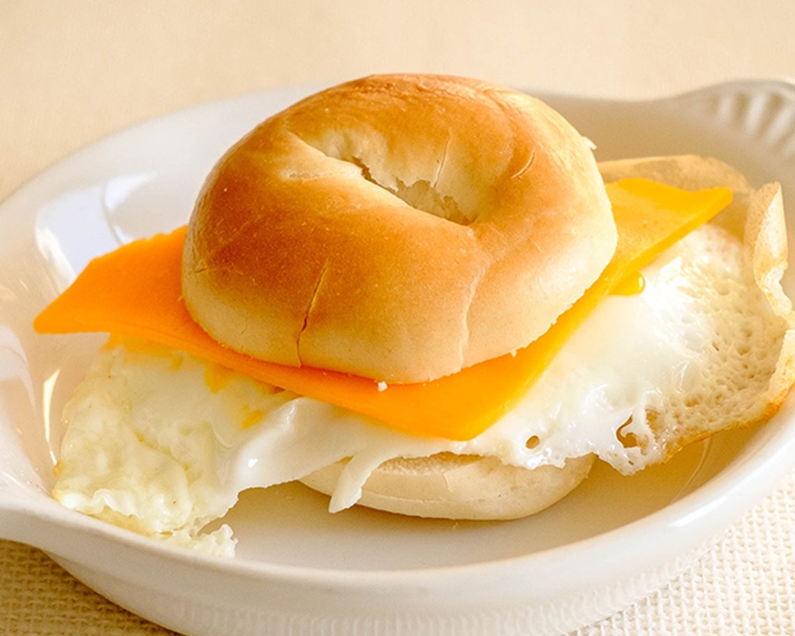 Round plate with a side view of an egg and cheese bagel breakfast sandwich.
