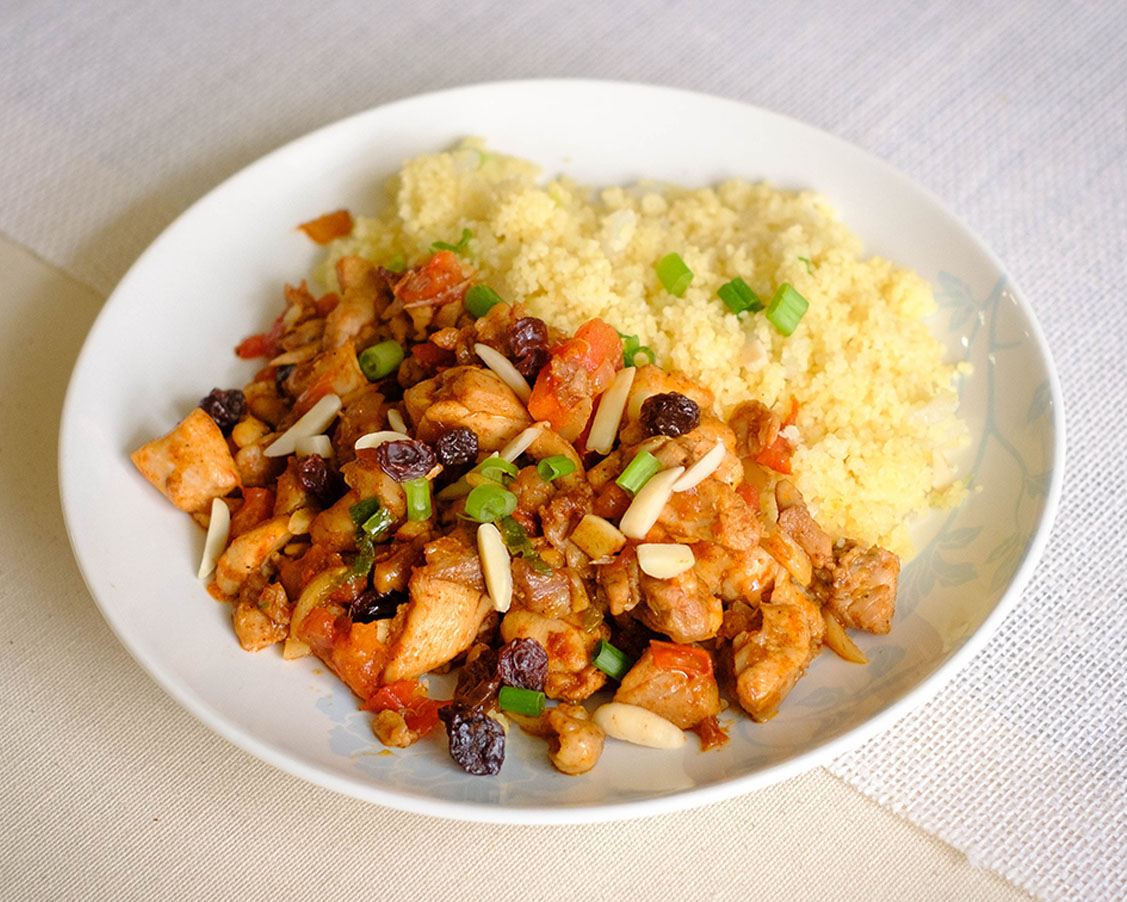white round plate with moroccan chicken and couscous.