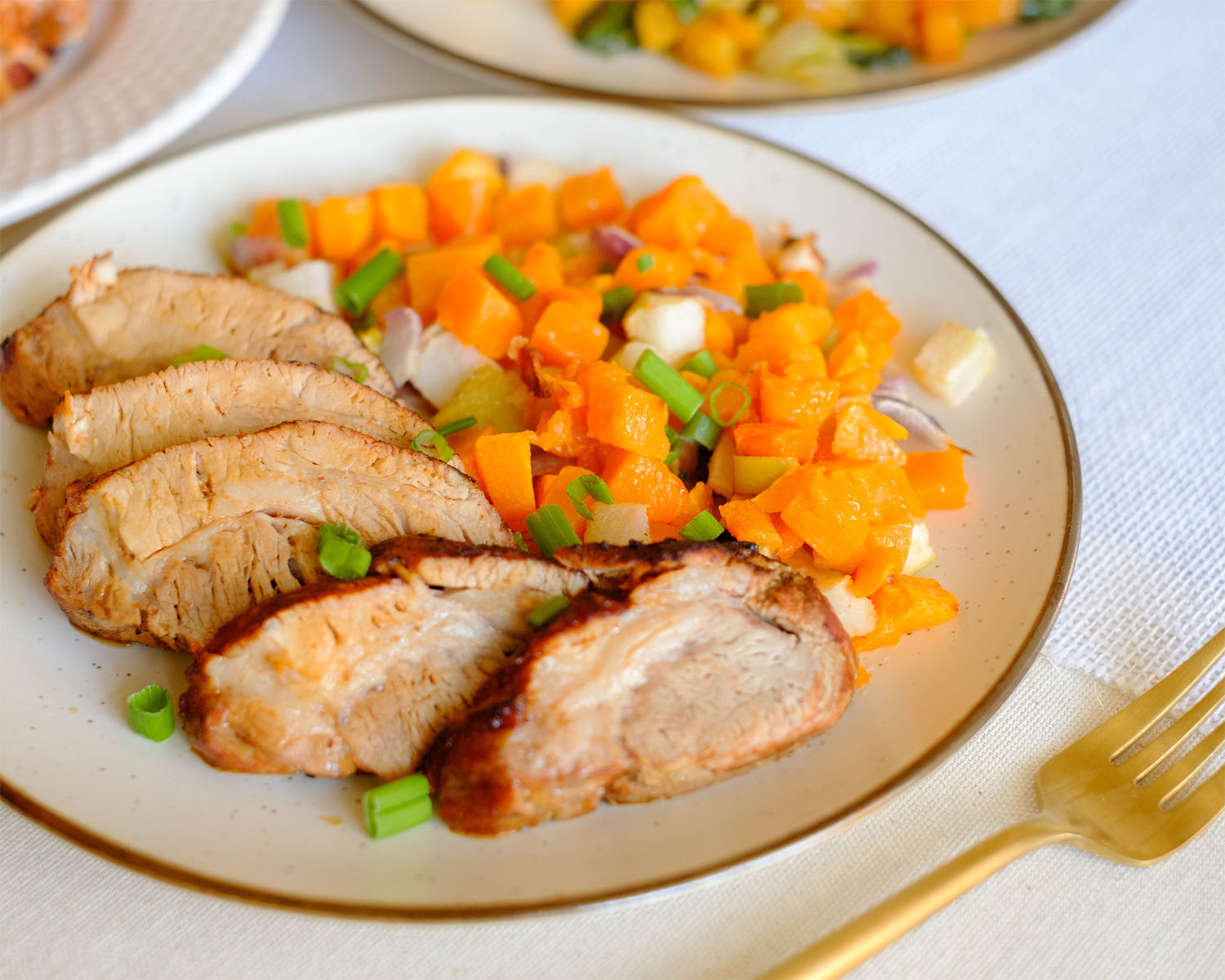 Round plate with sliced pork tenderloin and diced butternut squash.