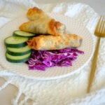 round plate with egg rolls, cucumber, and cabbage