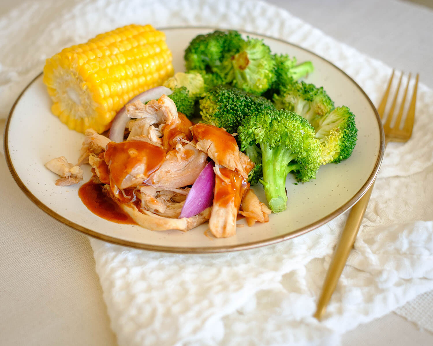 Round plate with shredded bbq chicken, corn, and broccoli