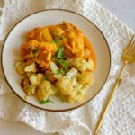 round plate with indian butter chicken and roasted cauliflower