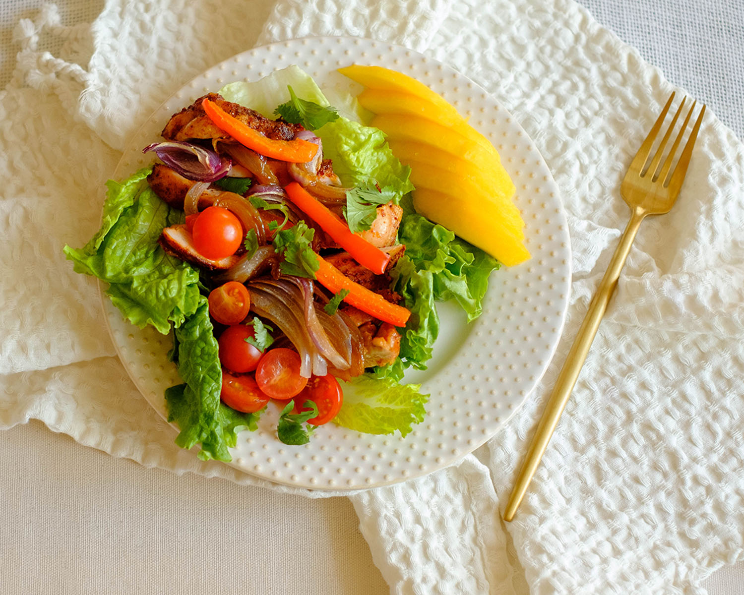 round plate with chicken fajita lettuce wrap and sliced mango