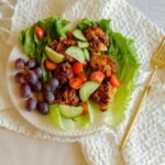 round plate with chicken meatball lettuce wraps served with grapes