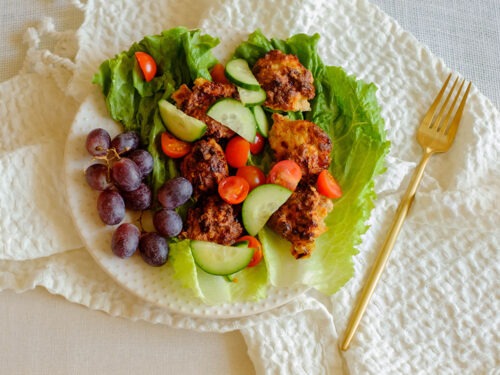 round plate with chicken meatball lettuce wraps served with grapes