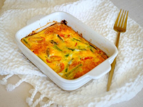 white rectangular baking dish with asparagus and tomato egg frittata