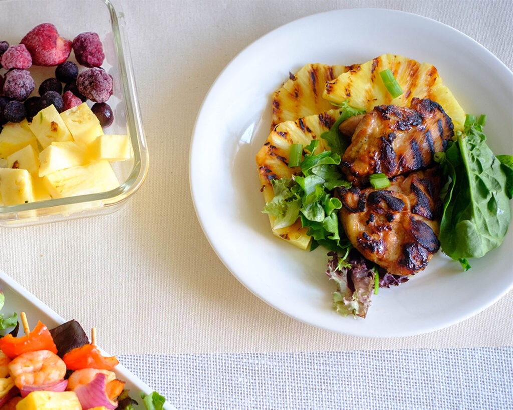 round plate with grilled chicken with grilled pineapple and crisp greens