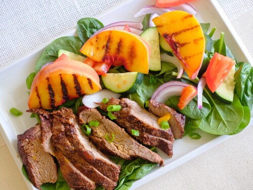 grilled peach and steak salad in rectangle plate
