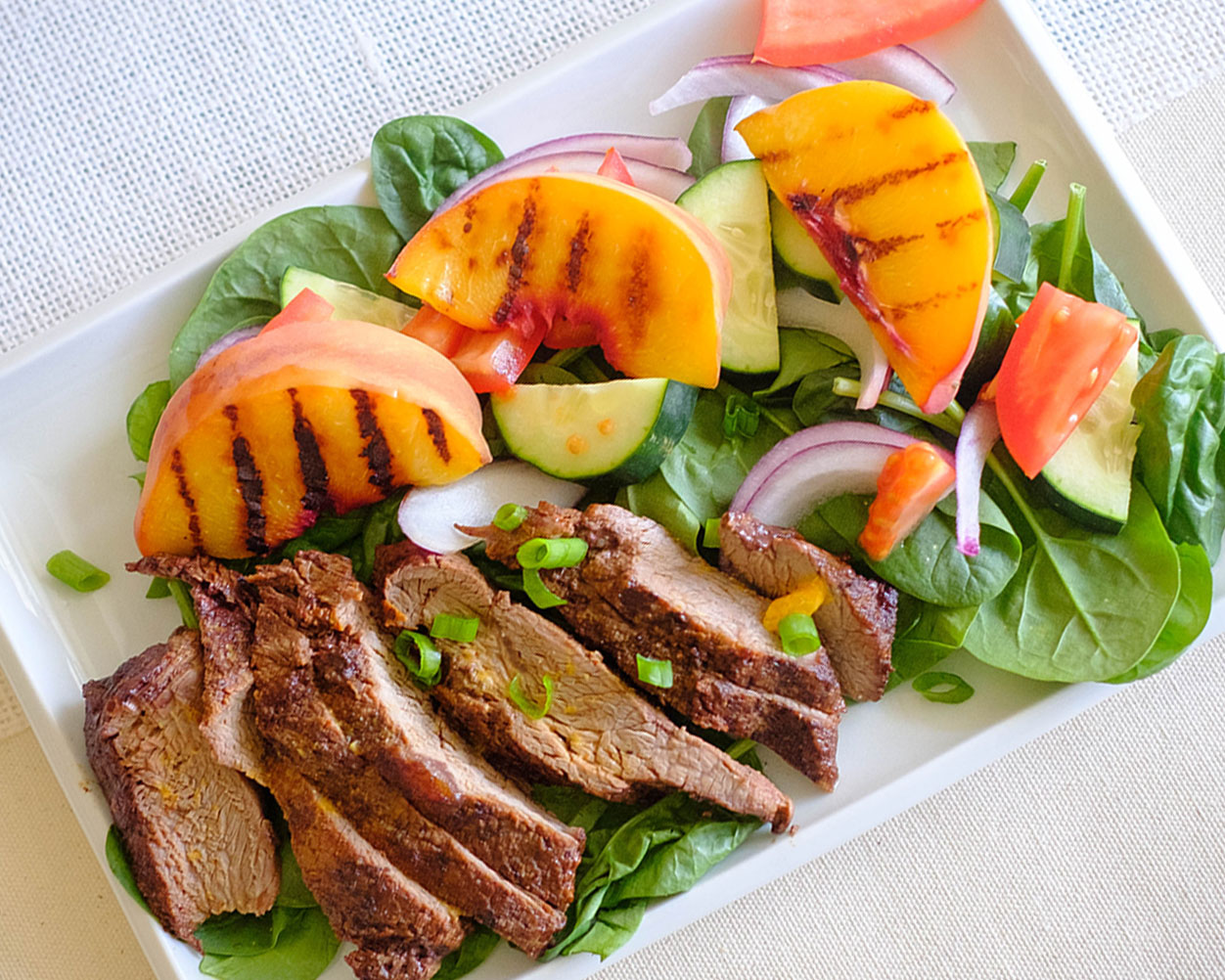 grilled peach and steak salad in rectangle plate