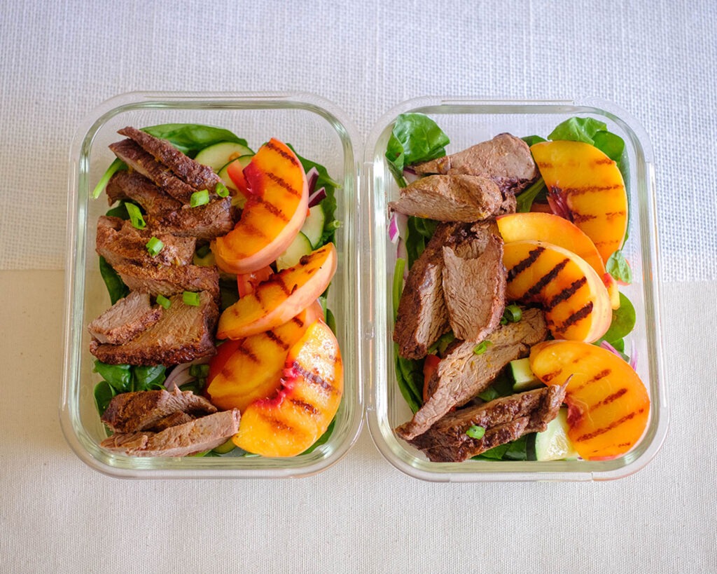 grilled peach and steak salad in meal prep containers