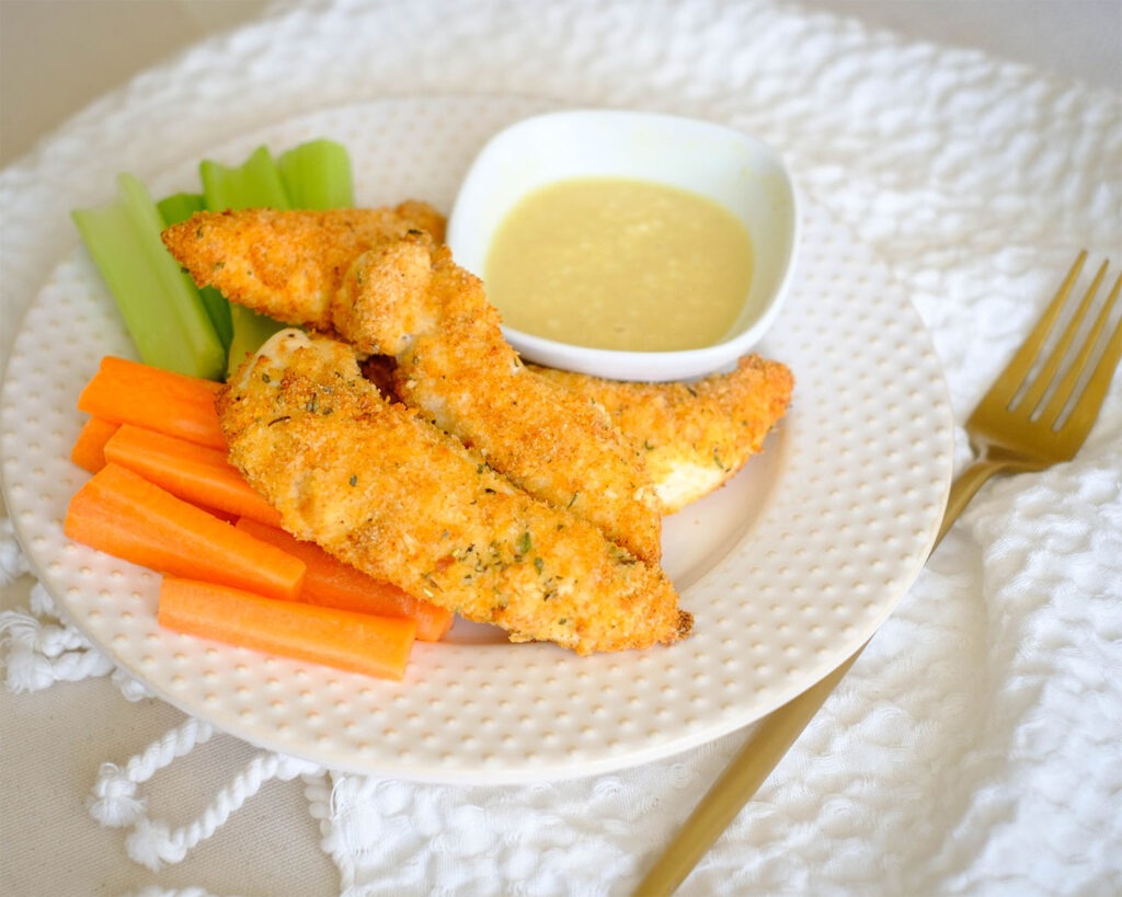 round plate with panko breaded oven baked chicken tenders and carrots and celery and honey mustard