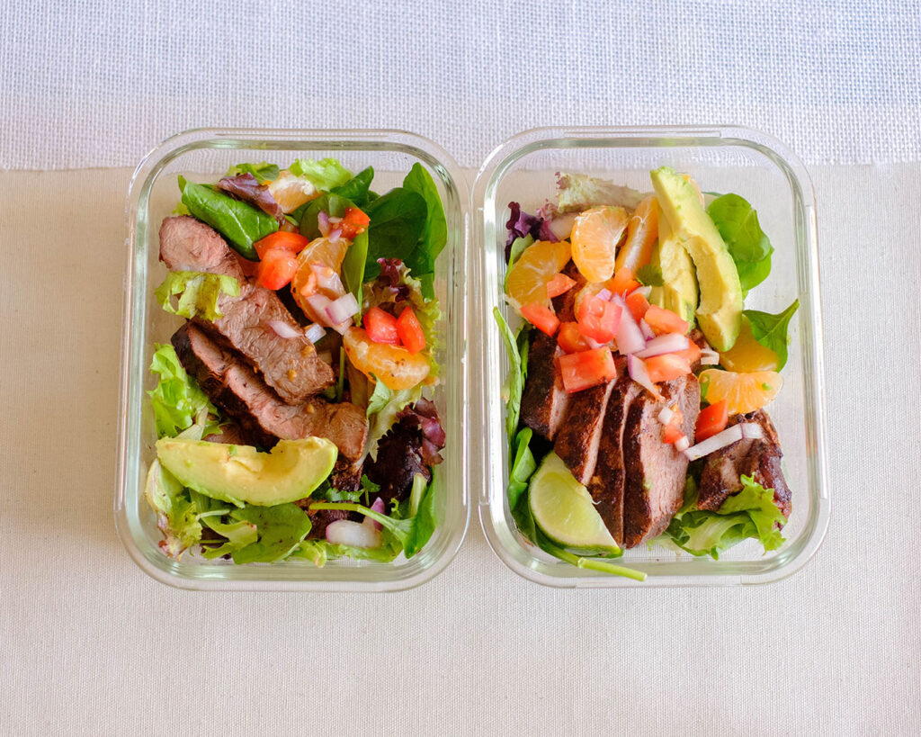 glass meal prep containers with steak and orange salsa