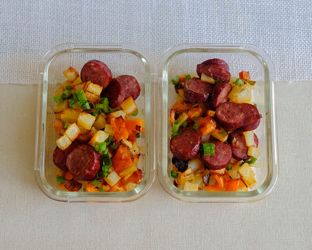 glass rectangle containers with sliced baked sausage and potato hash and peppers, and green onions