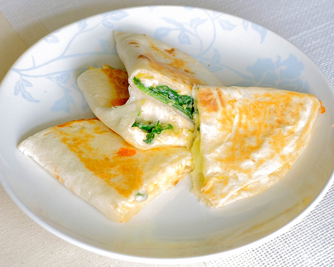 round plate with spinach and egg quesadilla