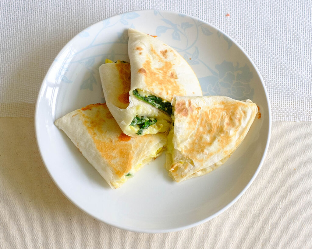 round plate with spinach and egg quesadilla