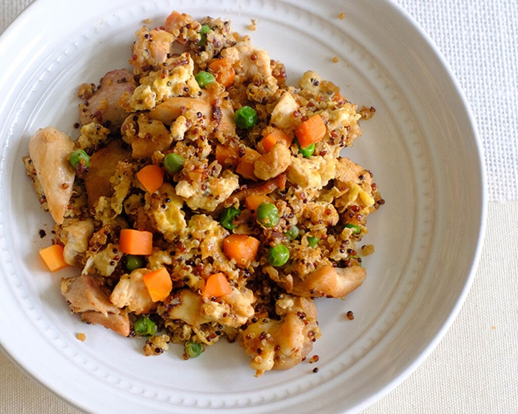 round plate with chicken fried rice, quinoa, scrambled eggs, peas, and carrots