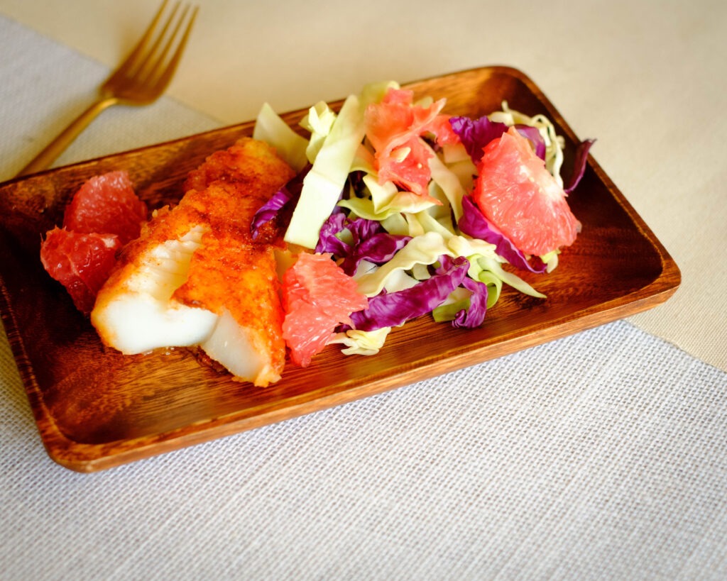 rectangular wooden plate with fish recipe of chile rubbed cod and grapefruit coleslaw