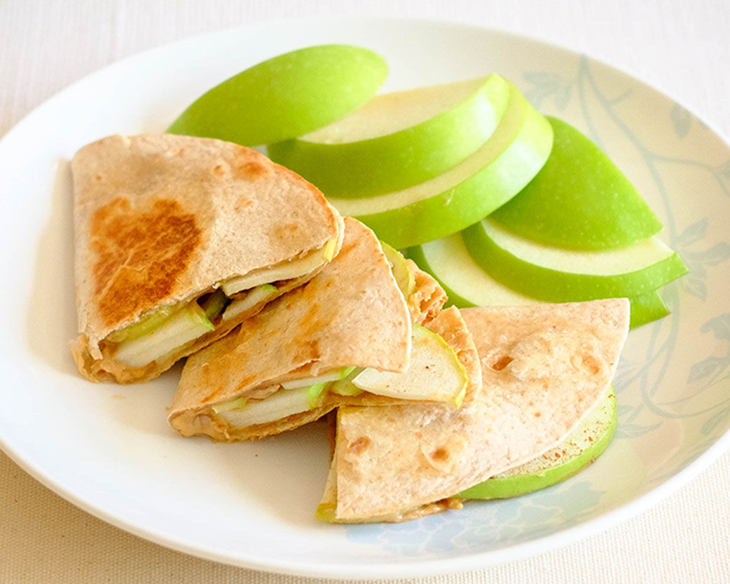 round plate with peanut butter quesadillas and sliced green apples