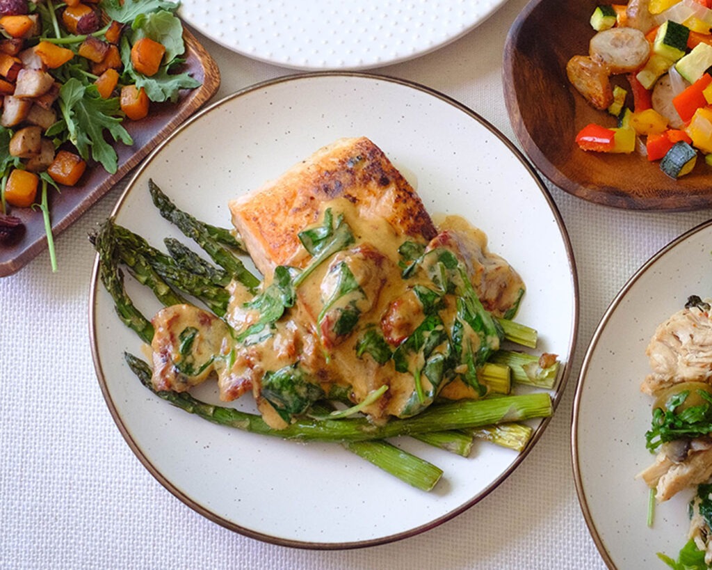 round plate with salmon with creamy sun-dried tomato sauce and asparagus