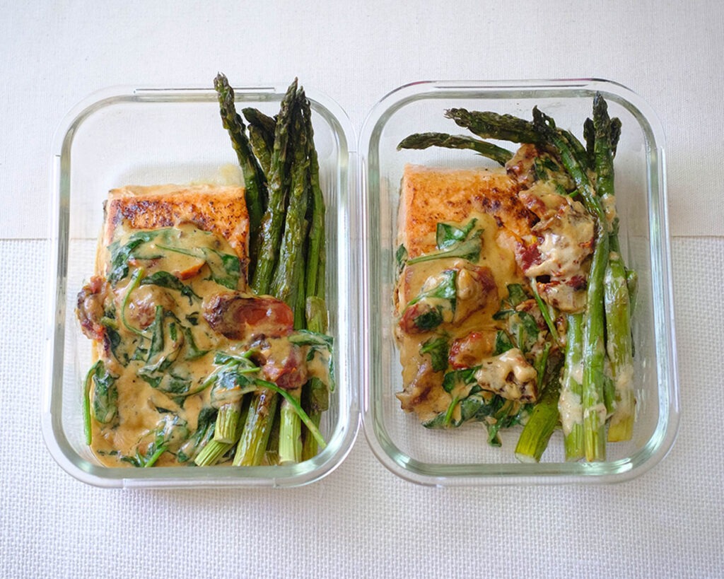 glass containers with salmon with creamy sun-dried tomato sauce and asparagus