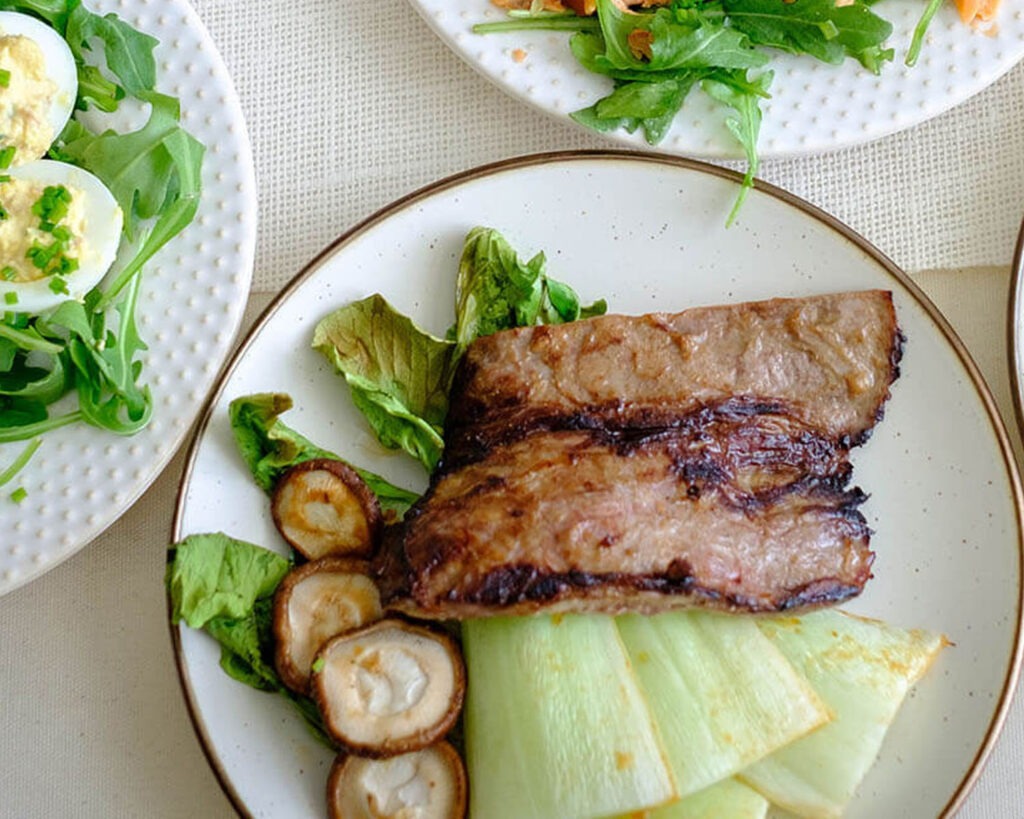 round plate with grilled skirt steak and roasted bok choy and shiitake mushrooms