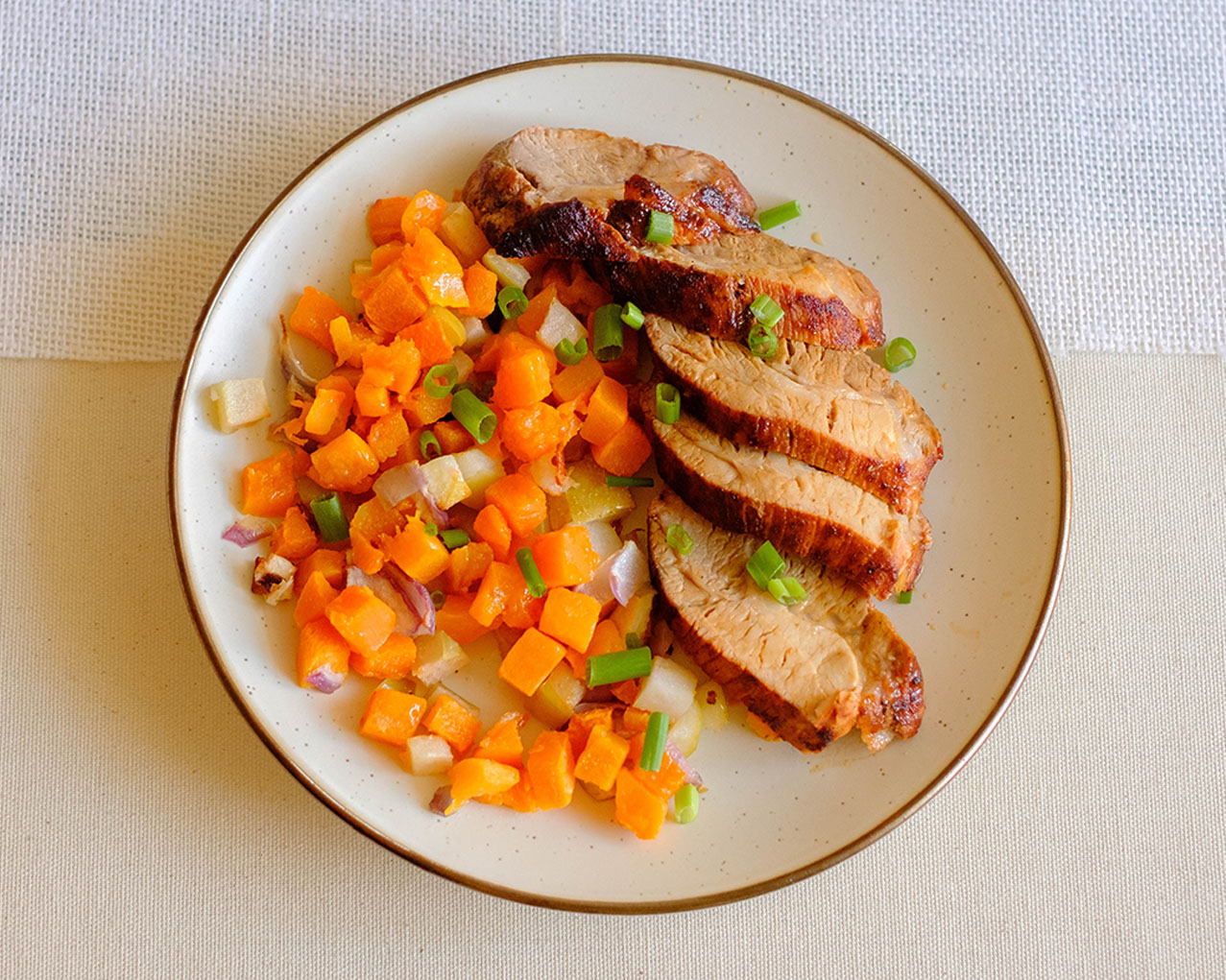 round plate with sliced pork tenderloin and diced butternut squash