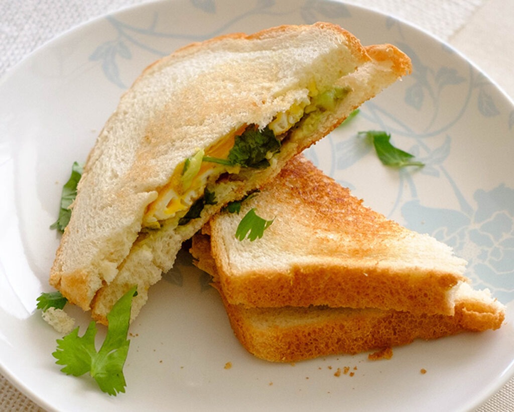 round plate with avocado and egg sandwich