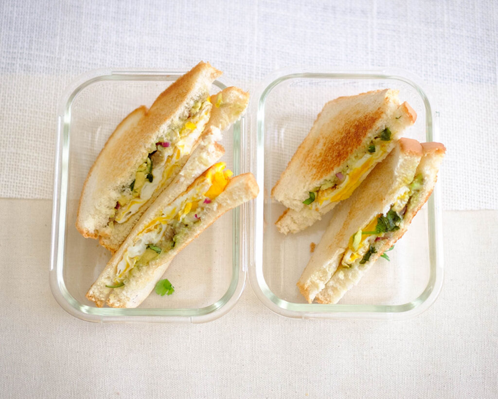 glass meal prep container with avocado and egg sandwich
