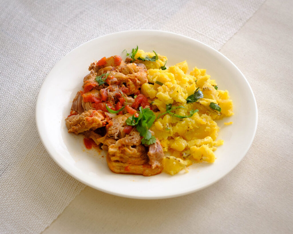 round plate with shredded pork with mashed plaintains