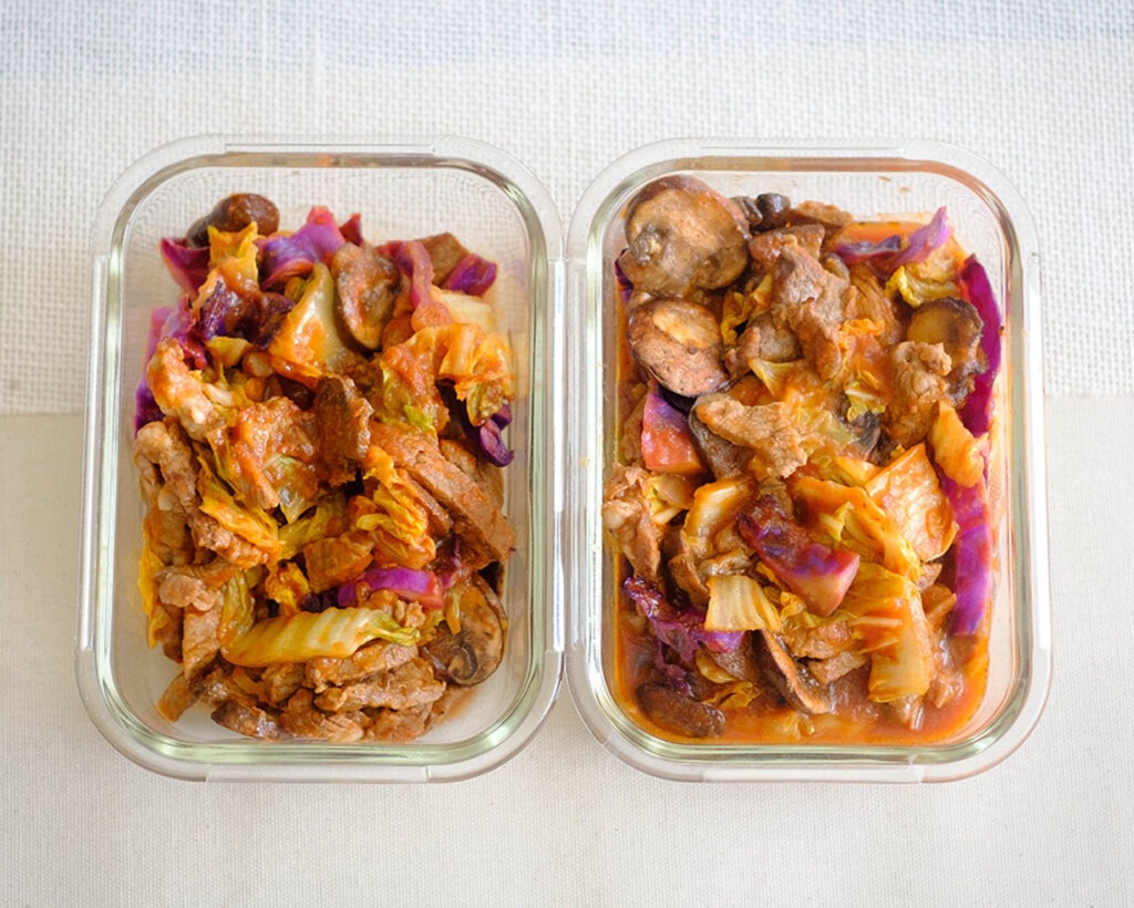 glass meal prep containers with beef chunks in tomato sauce with napa cabbage, red cabbage, and sliced mushrooms