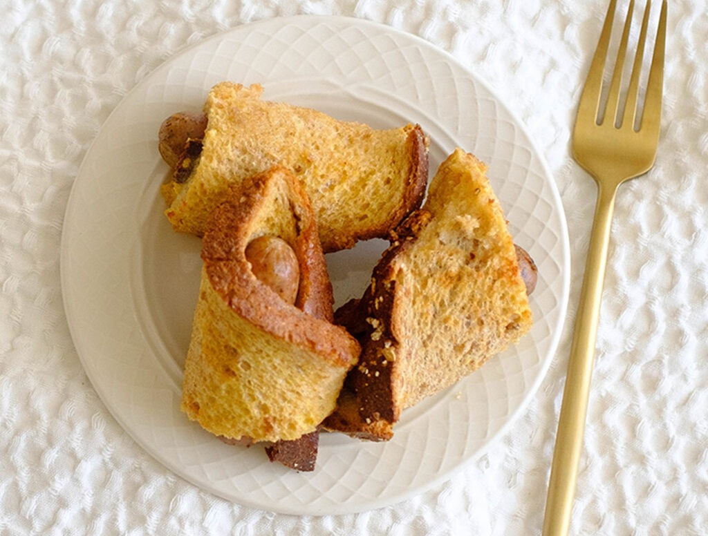 round white plate with sausage rolled up in french toast