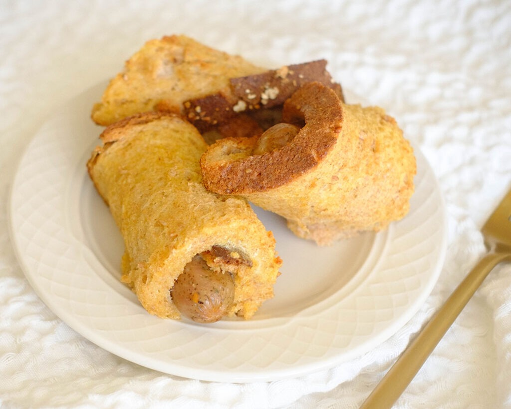 round white plate with sausage rolled up in french toast