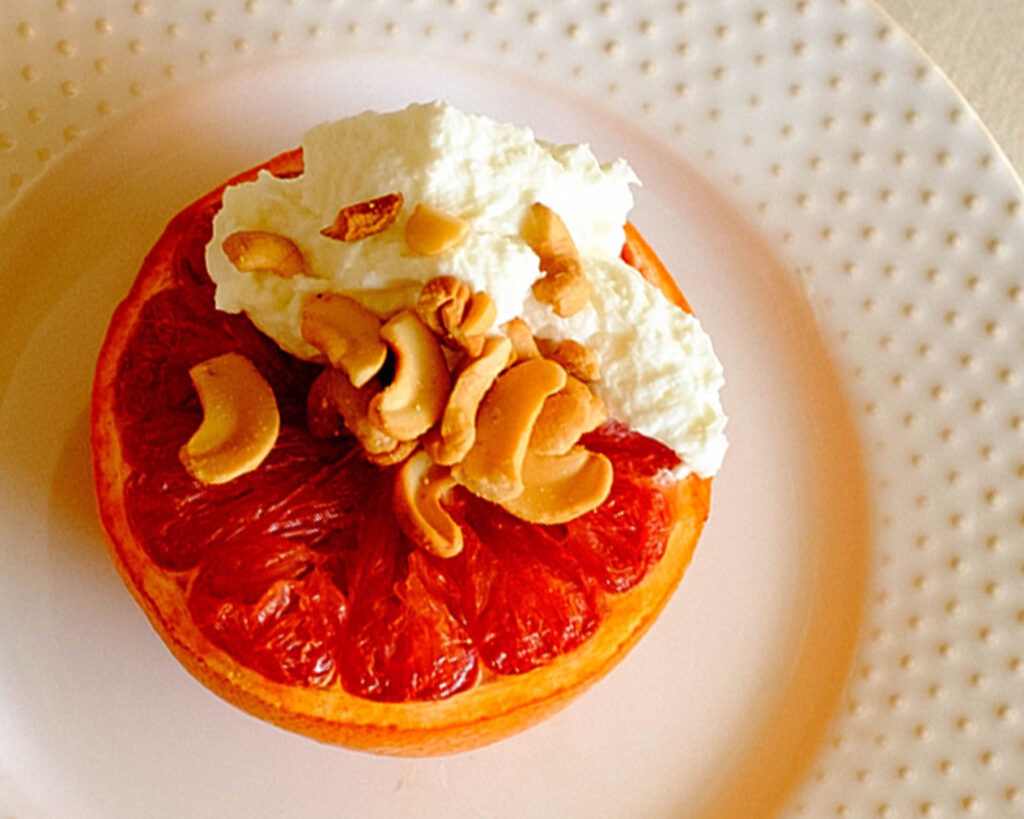 round plate with grapefruit topped with yogurt and cashews