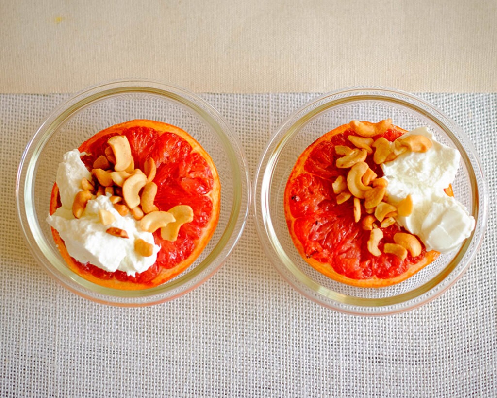 round glass meal prep containers with grapefruit topped with yogurt and cashews