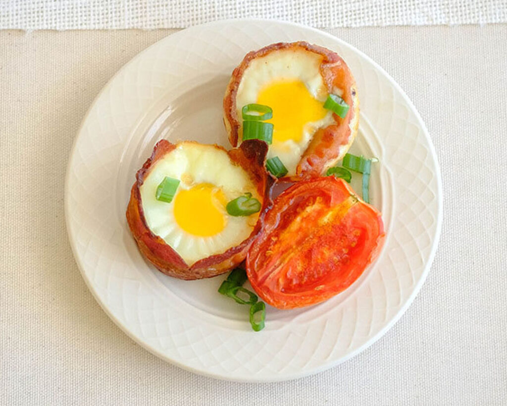 round plate with bacon wrapped eggs and roasted tomato