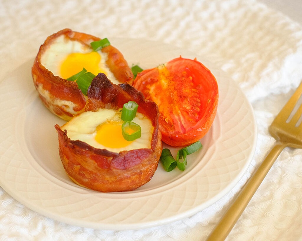 round plate with bacon wrapped eggs and roasted tomato