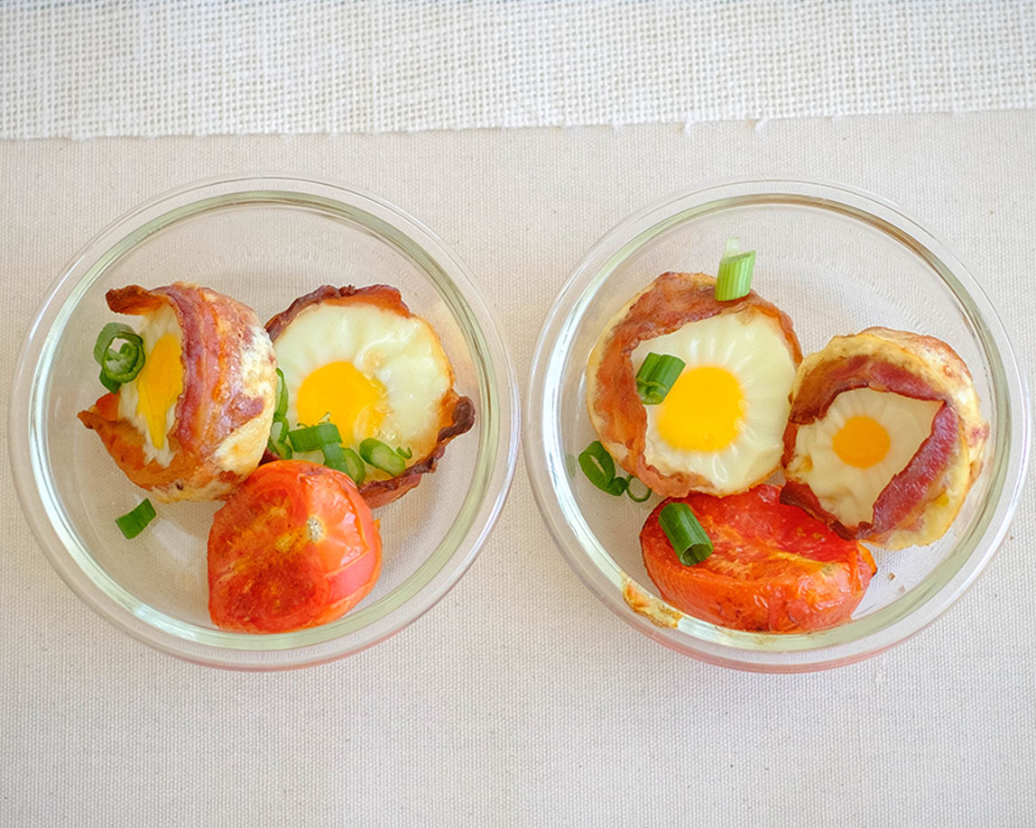 round glass meal prep containers with bacon wrapped eggs and roasted tomato